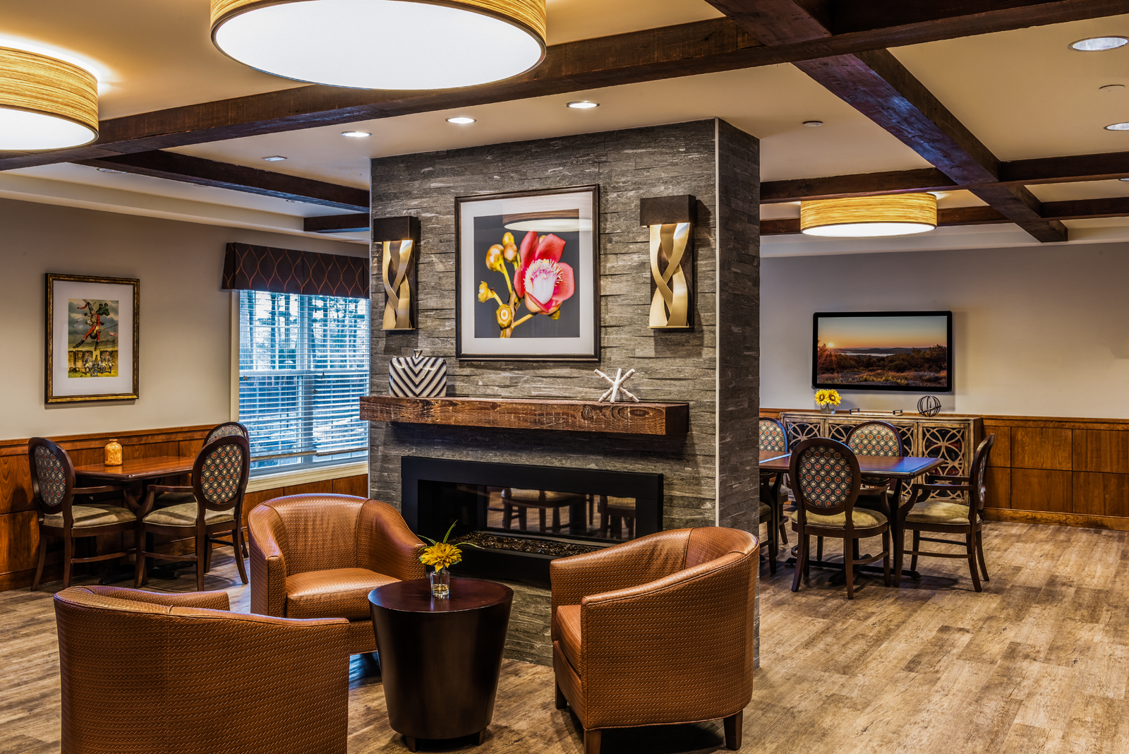 A fireplace brings the cozy to this rustic interior design of the social meeting area of an assisted living community .